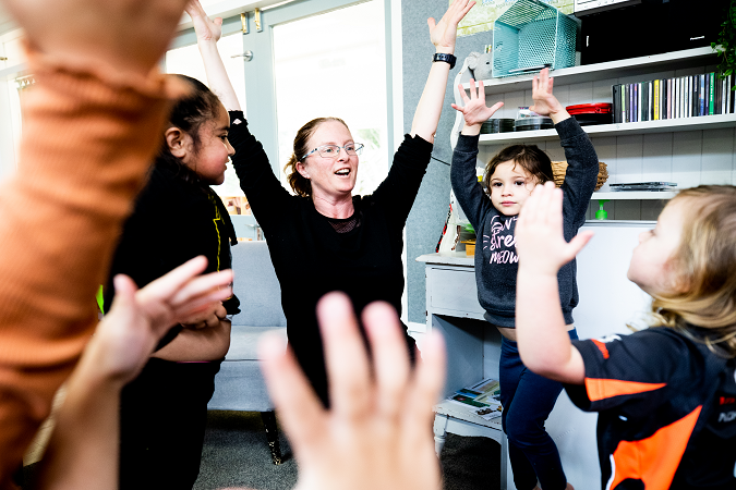 A kaiako working with a group of children doing actions