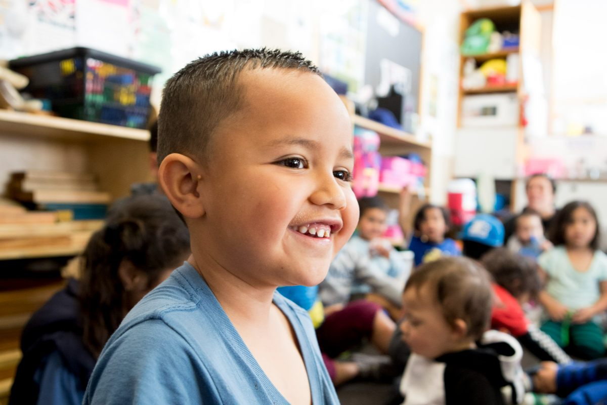 A child happy and smiling in a group at his early learning service