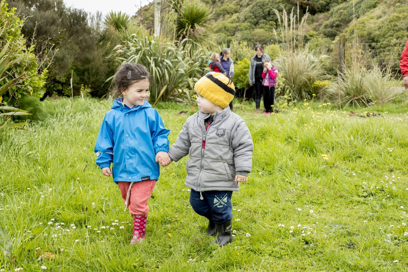 Two children holding hands in the grass