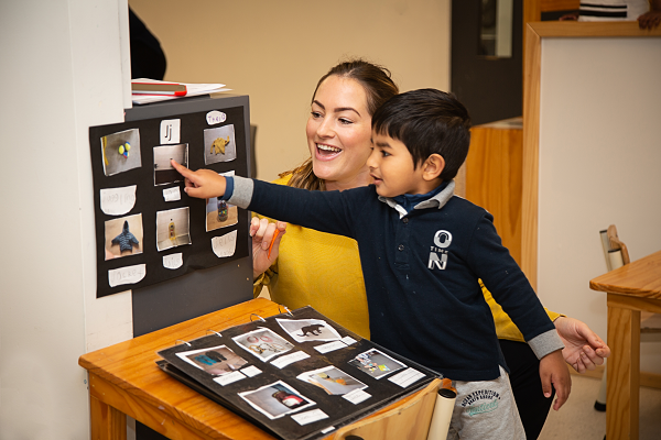 Kaiako supporting a child pointing at images of items starting with different letters