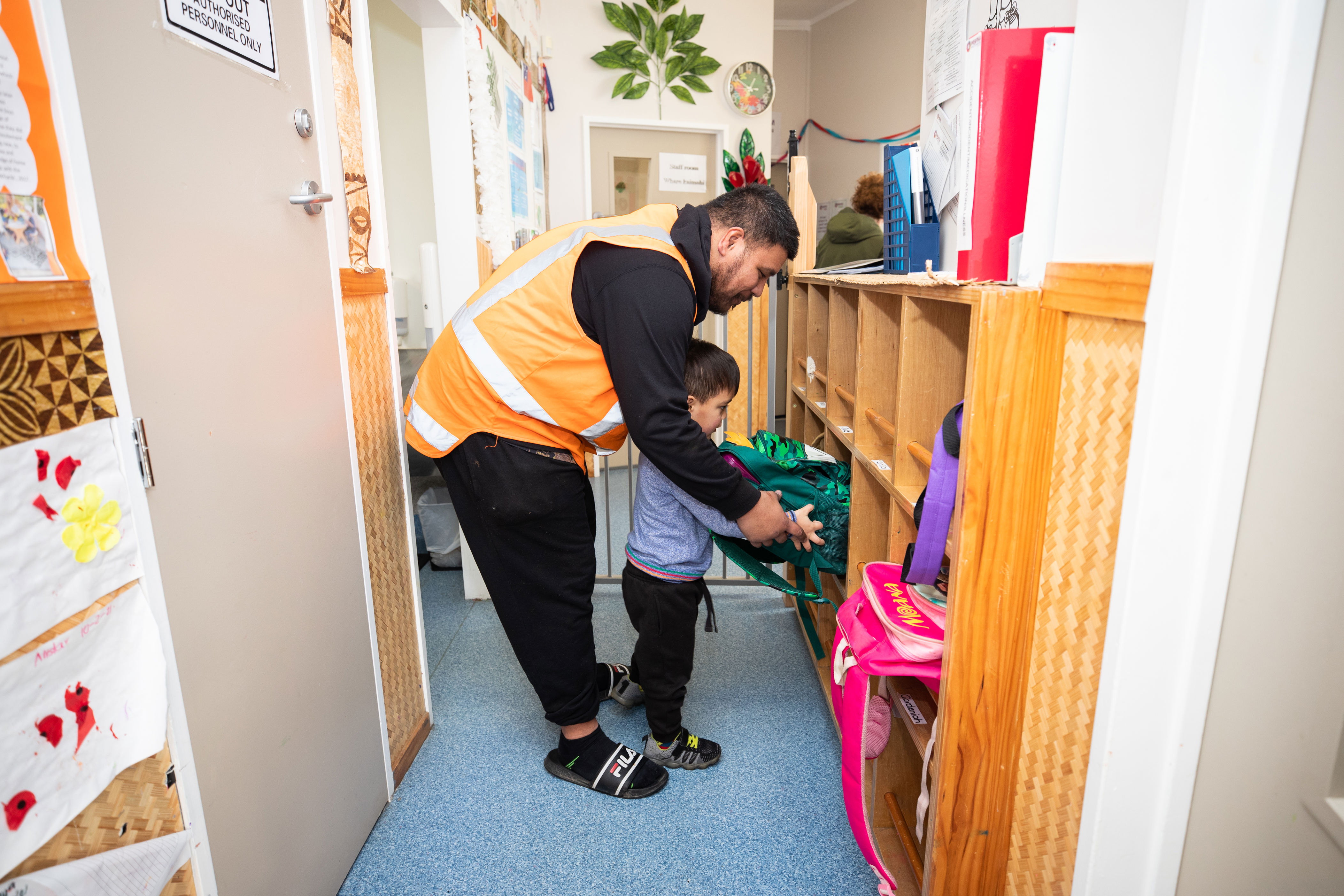 A parent helping a child put their bag away at their early learning service.