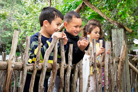  Children smiling and looking over fence.