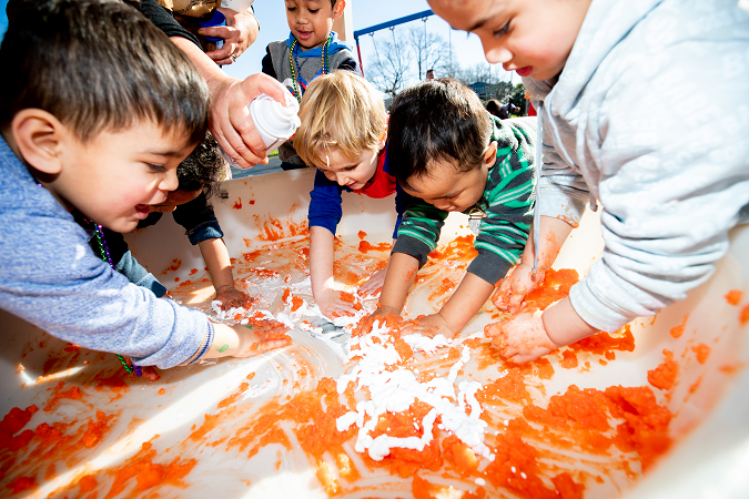 Children playing in a container of goop with their hands