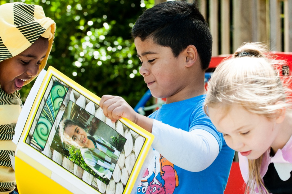 Three children are reading outside.