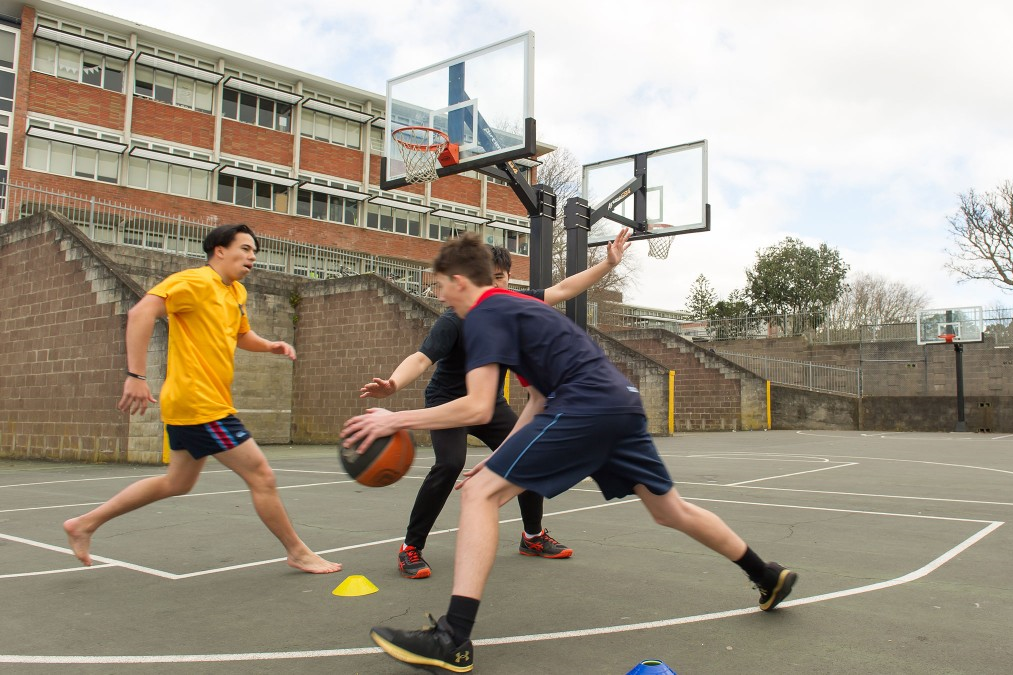 Three teenage boys playing basketball.