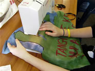 Close up of students hands guiding fabric through a sewing machine.