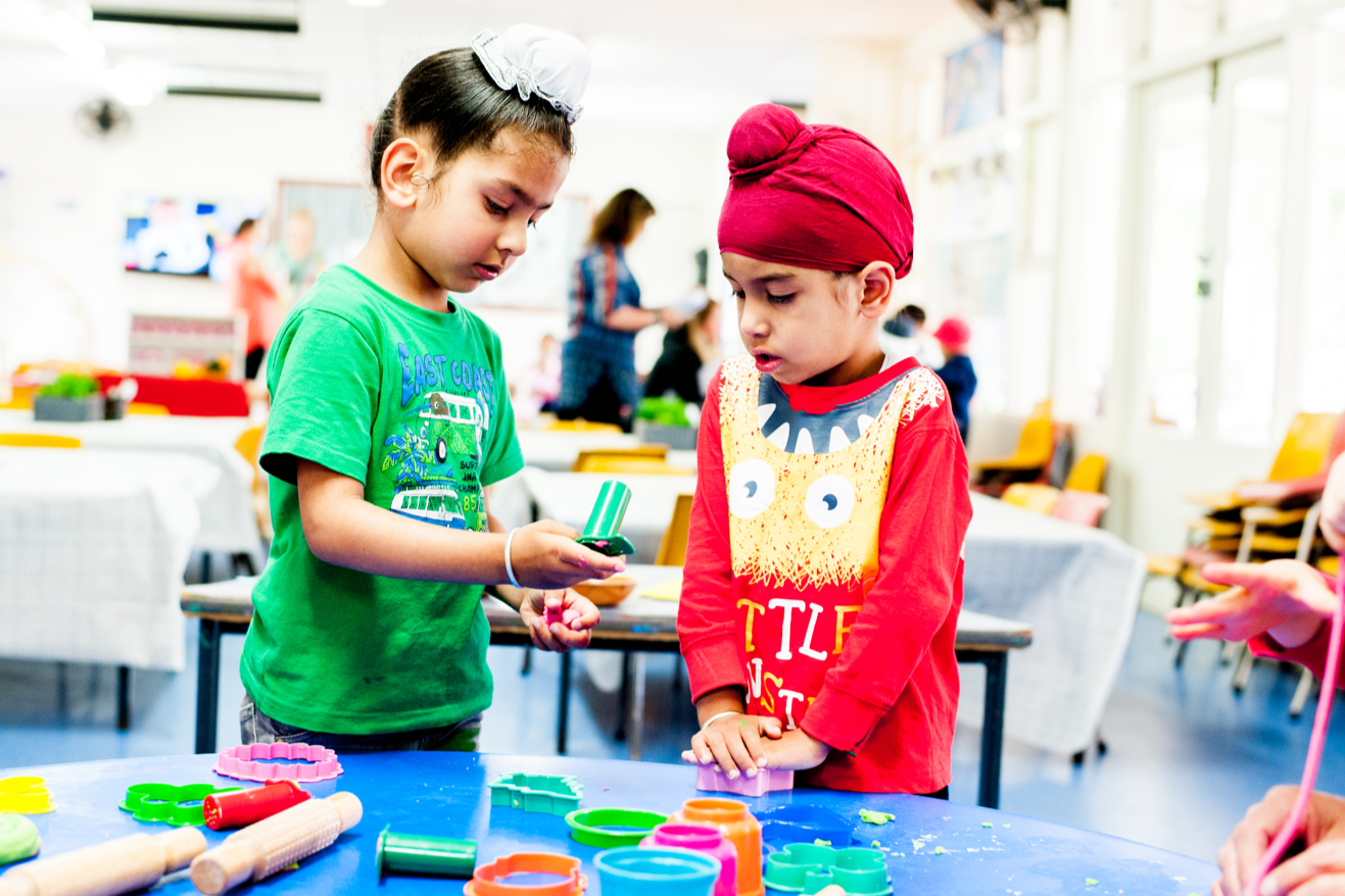 Two tamariki from different cultures playing together with play dough