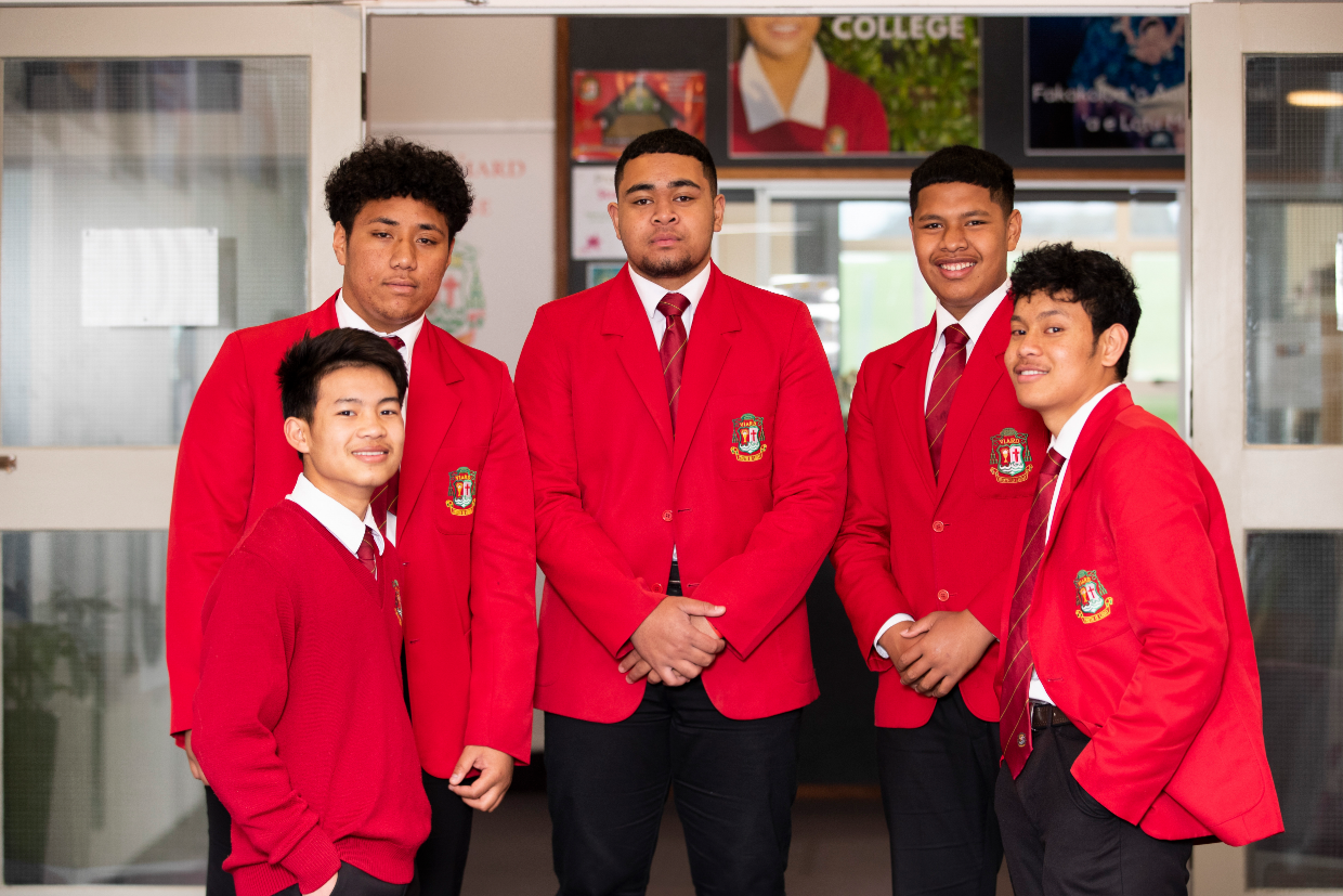 group of 5 boys standing outside a classroom in a red uniform