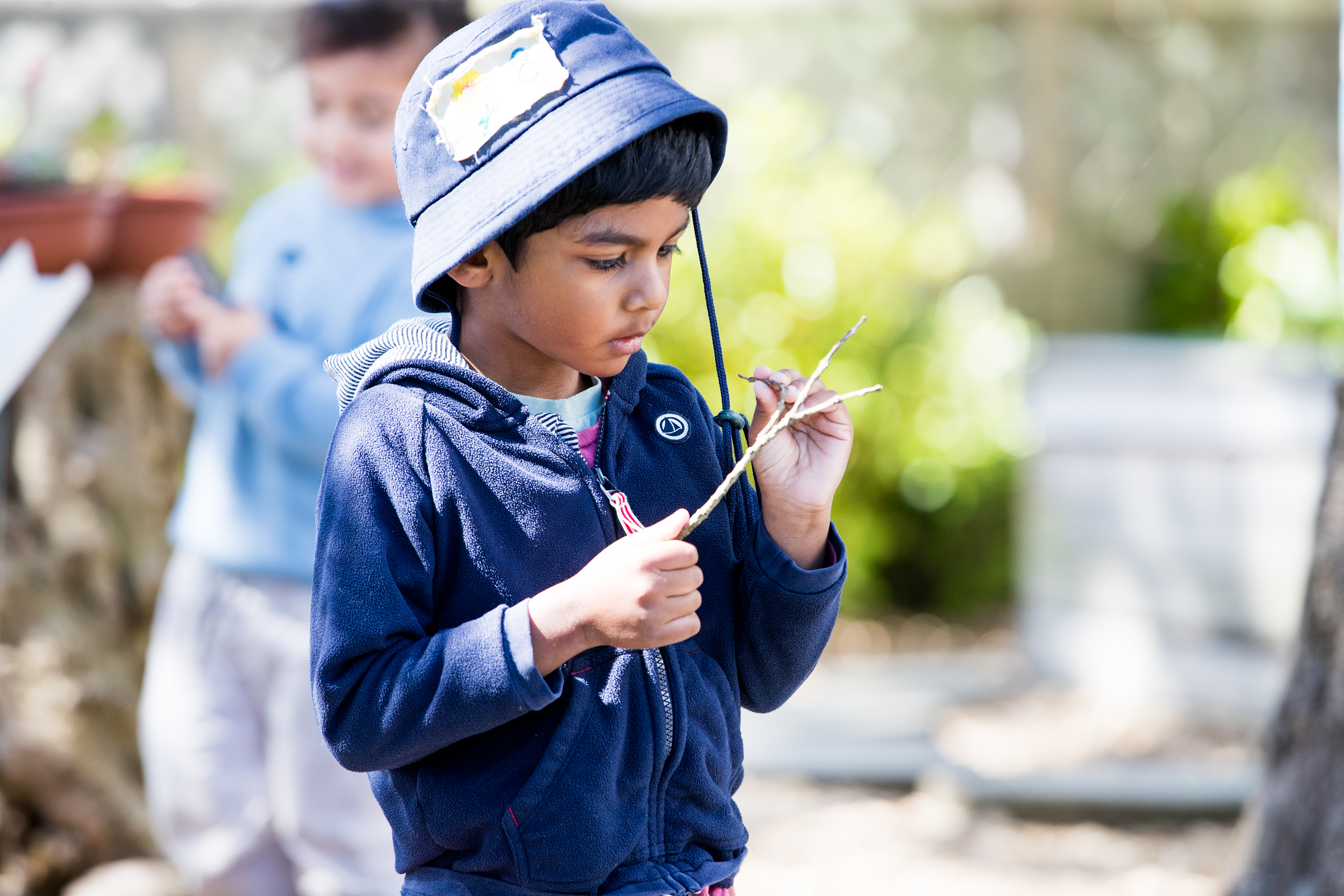 A young child outside playing with a piece of wood.