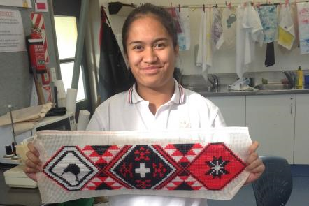 Student smiles while showing her tāniko to the camera.