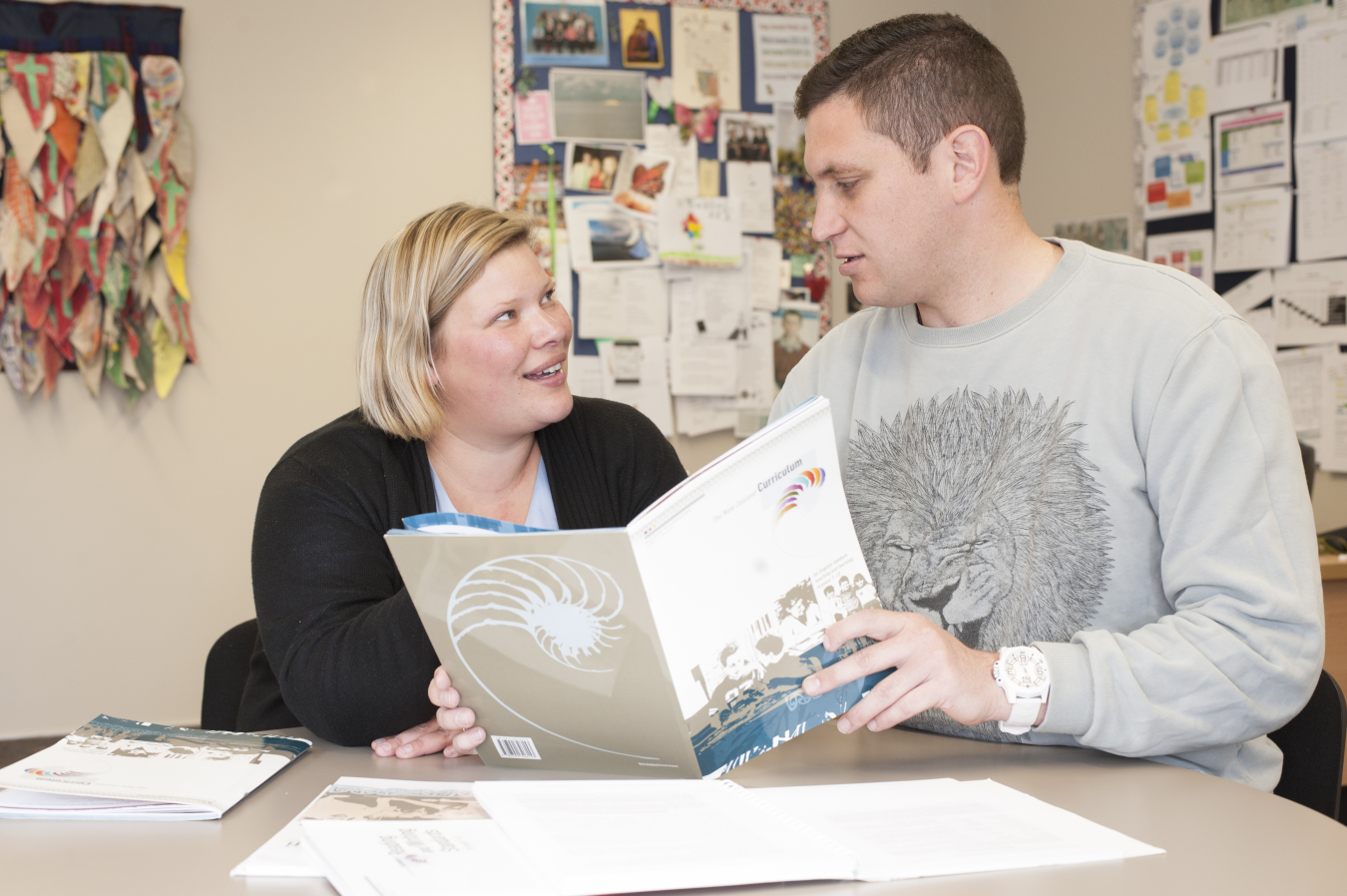 two teachers looking at a learning workbook