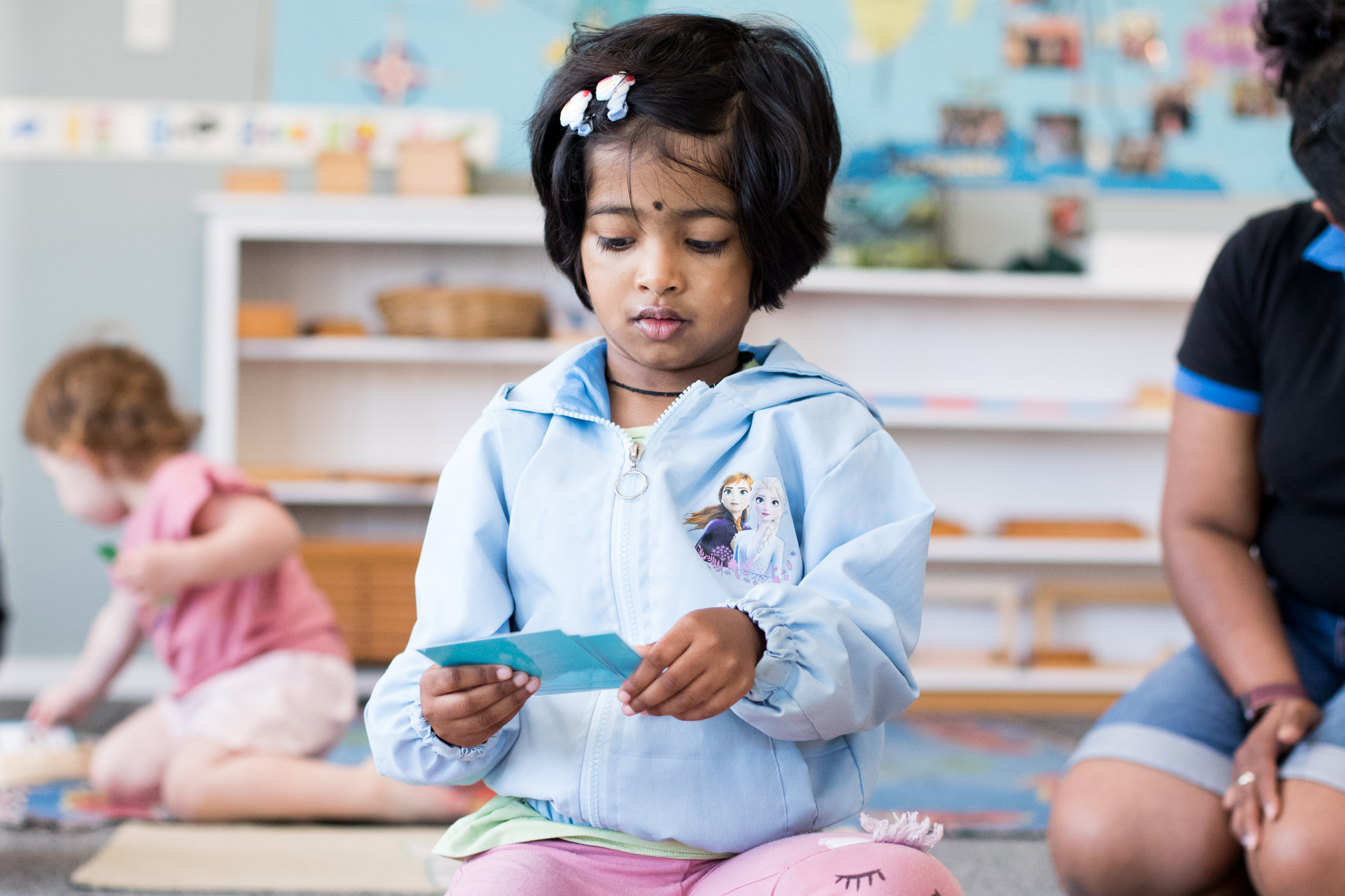 young child sitting on the floor sorting learning cards