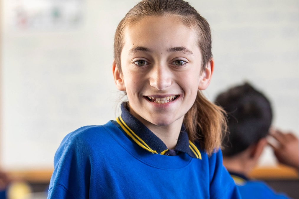 A young ākonga smiles directly at the camera.