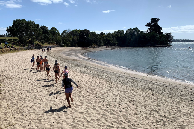 A group of students running down a beach.    