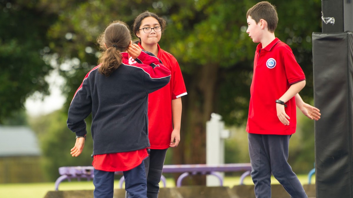 Three students in the playground talking. 