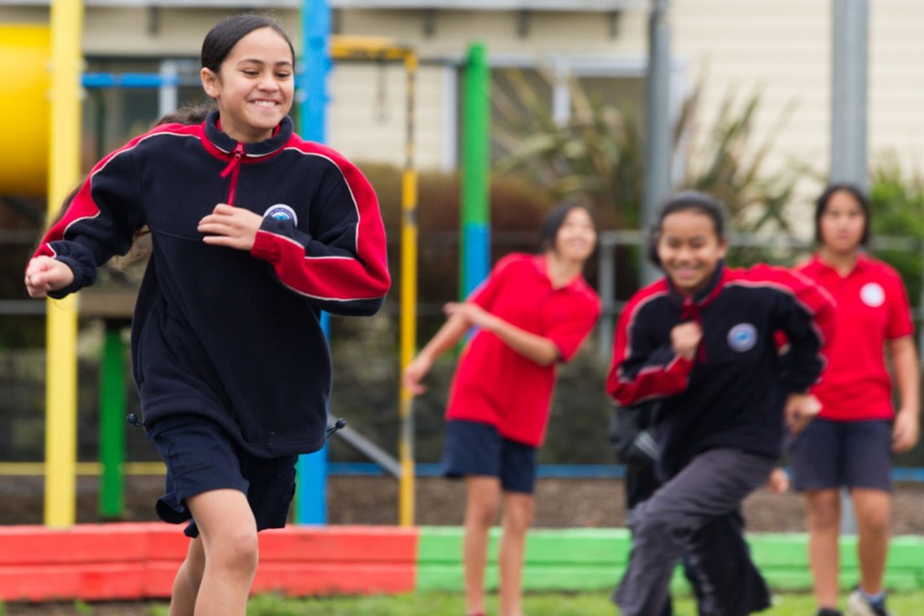 A group of girls playing a game outdoors and running.