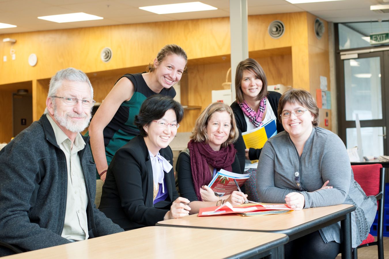 Six Kaiako sit at the table smiling at the camera.