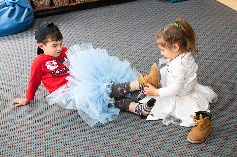 One tamariki helps another with taking off shoes