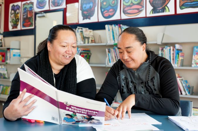 Two maori women working at a desk.