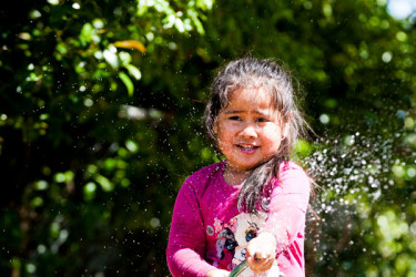 Tamariki playing with a hose outdoors
