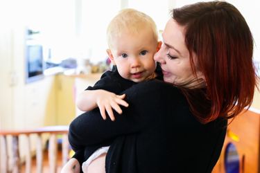 A woman holding an infant who's looking at the camera.