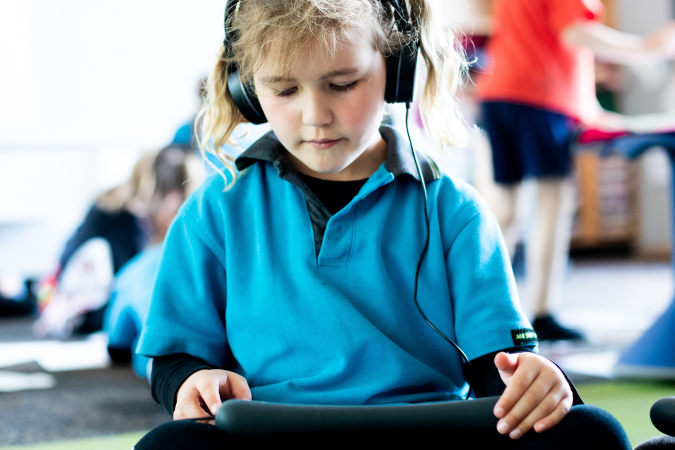 Child sitting on floor, crossed-leg watching something on laptop on her lap