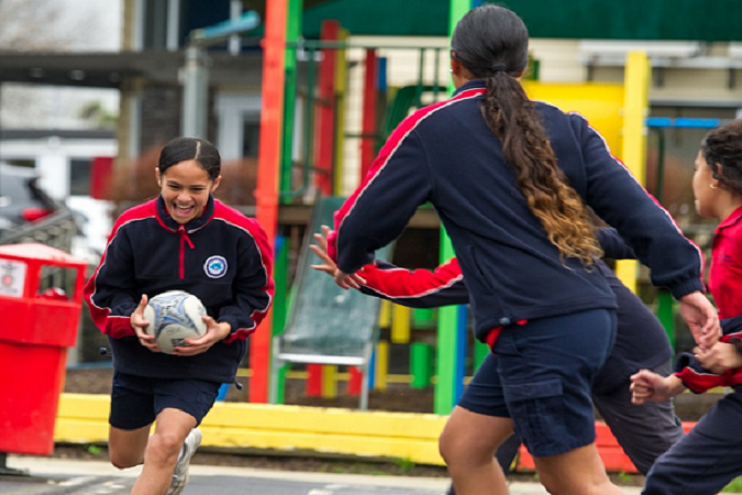 Tamariki play rugby together on the school field