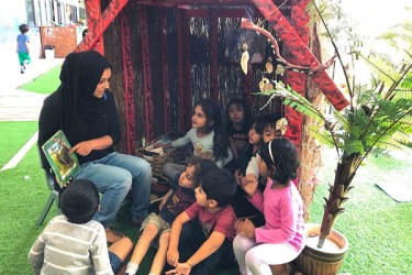 Children and teacher reading in a multicultural class outside