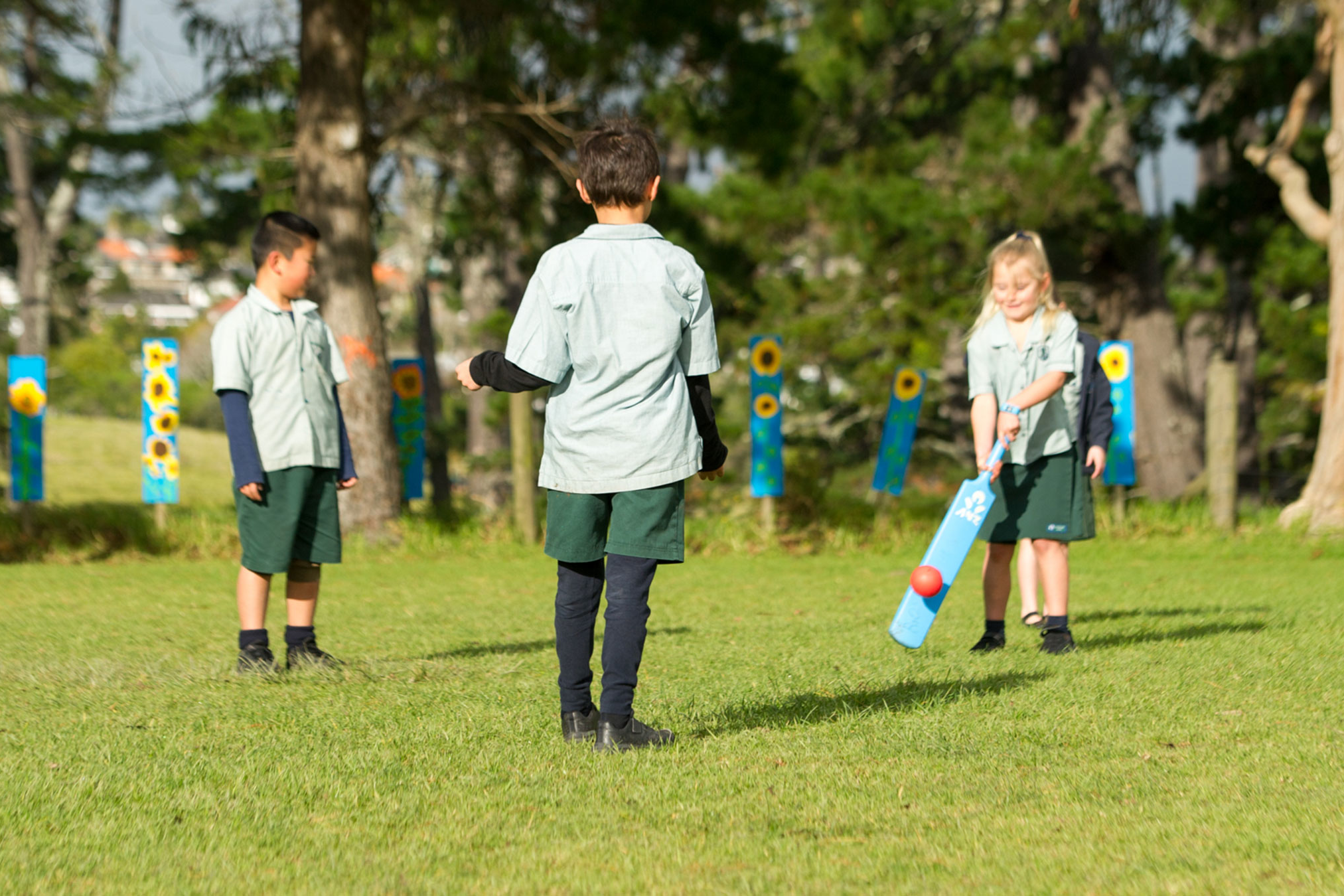 Students playing a game of cricket on a field.