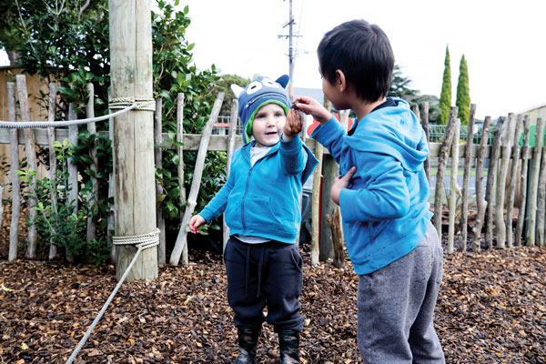 Two children in a playground playing with bark.
