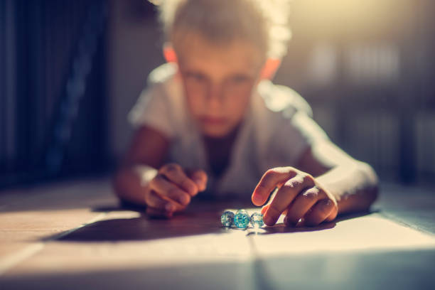 photo of little boy playing with glass marbles 