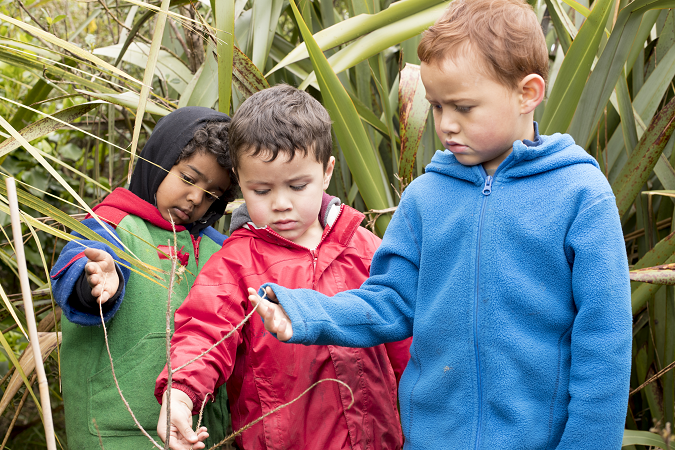 Three children touching the grass