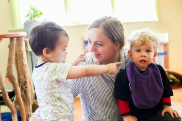 A kaiko engaging with two toddlers.