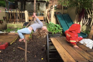 A child playing on a rope swing outside.