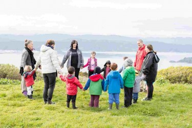 Children and kaiako standing in a circle overlooking the hills and harbour.