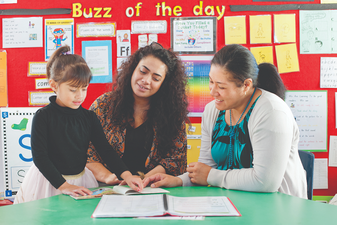 Child reading with kaiako and parent