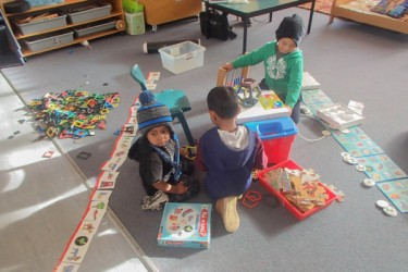 Children playing on the floor with puzzles and toys.