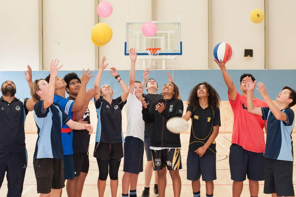 A group of students and a teacher throwing balls into the air.