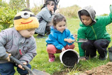 Children gardening together with a bucket and spade.