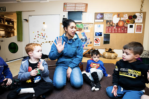 kaiako and children sitting on the floor in a classroom