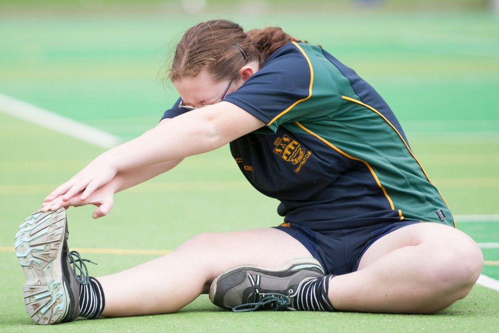 A teenage student doing a leg stretch.