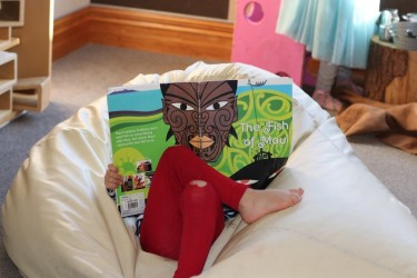 A child reading book about Maui on a bean bag.