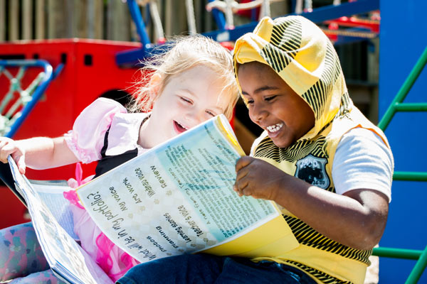 Two tamariki enjoying looking at their learning stories together.