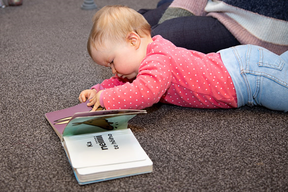 A kaiako and infant reading a book in te reo Māori