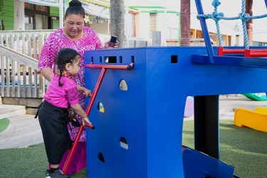 A child climbing a ladder while talking with a kaiako