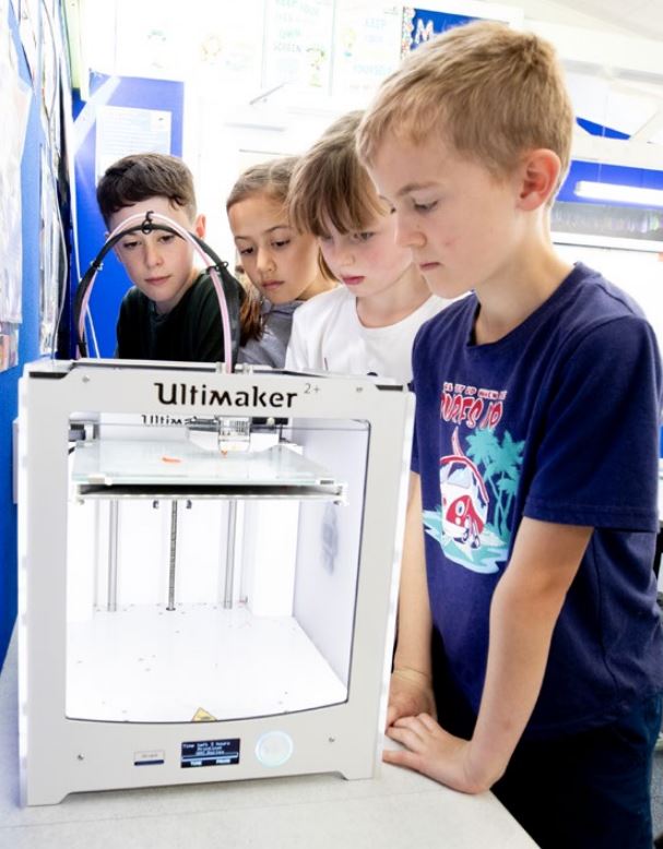 Four students looking at a 3D printer .jpeg