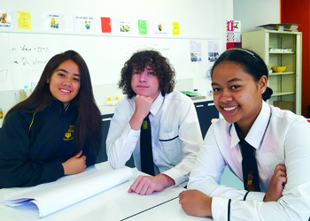 Three highschool students working in a class together