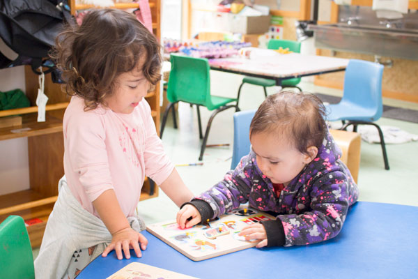 Two young children playing with a puzzle