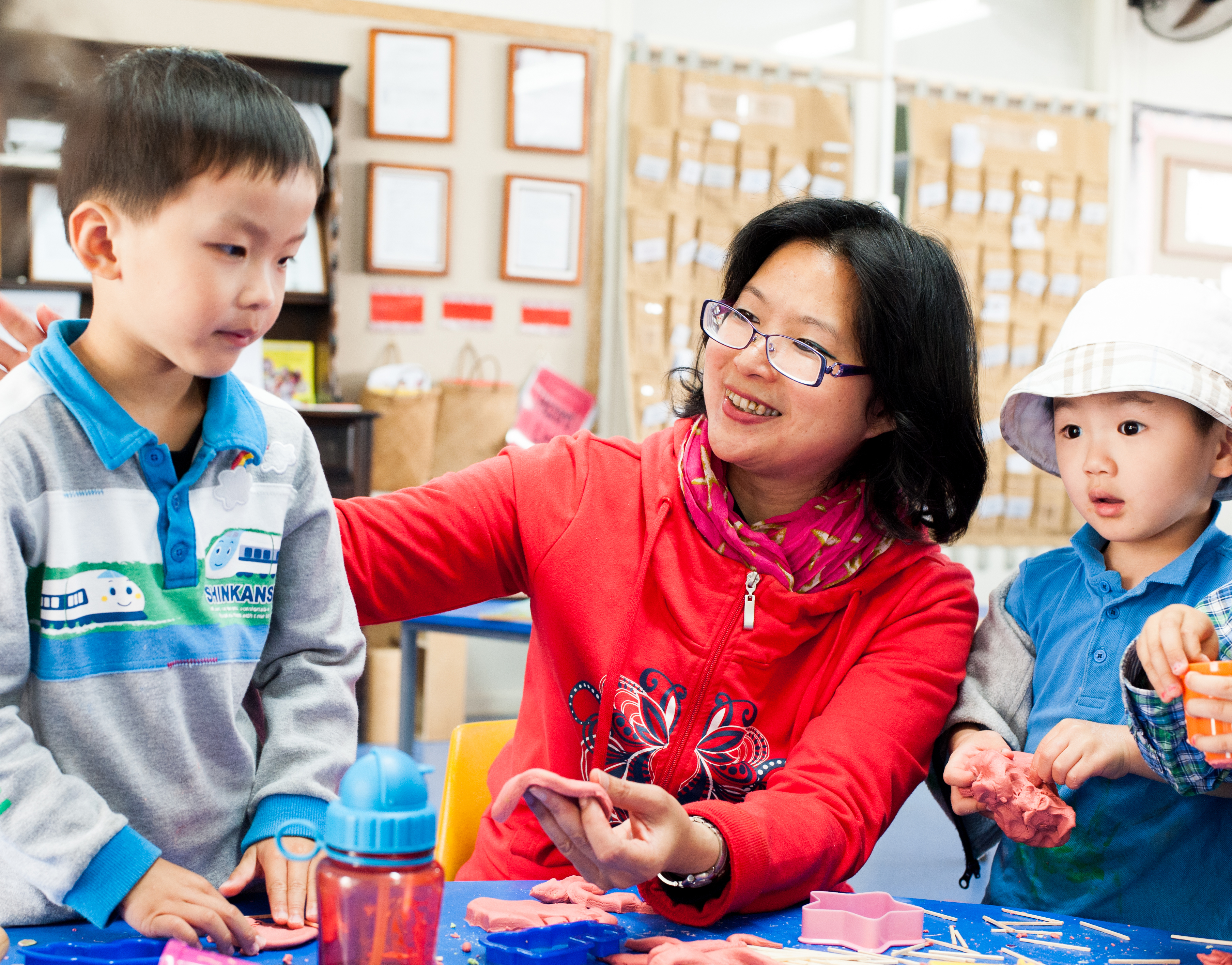 Two children using playdough with a kaiako.