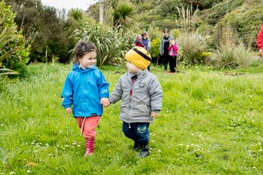 Children holding hands walking through a field.